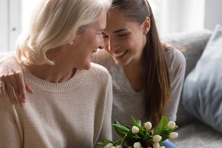 Loving adult daughter greeting mom with flowers