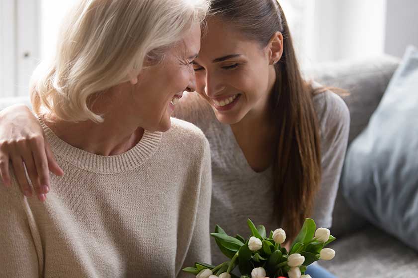 Loving adult daughter greeting mom with flowers Loving adult daughter greeting mom with flowers
