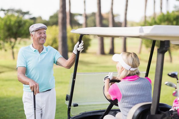 Man looking at woman sitting in golf buggy