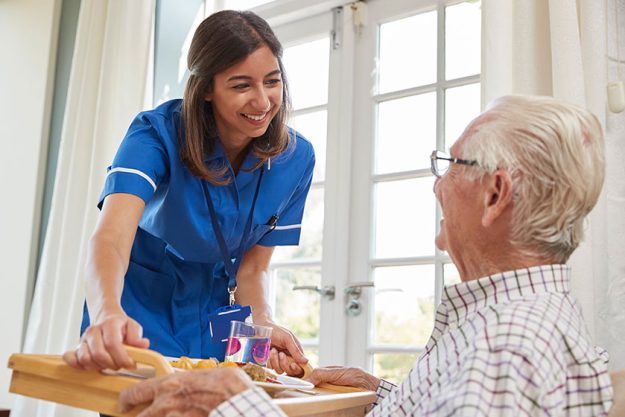 Nurse serving dinner to a senior man Nurse serving dinner to a senior man