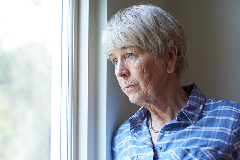 Senior Woman Suffering From Depression Looking Out Of Window