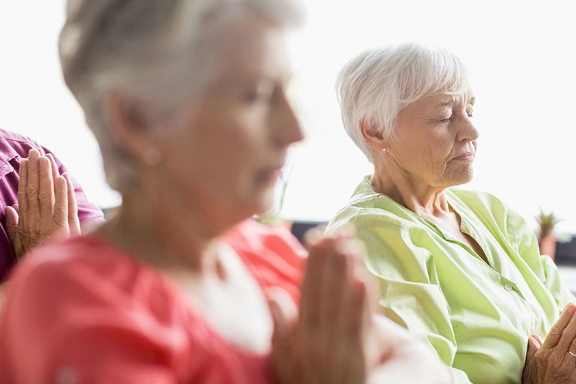 Seniors doing yoga with closed eyes