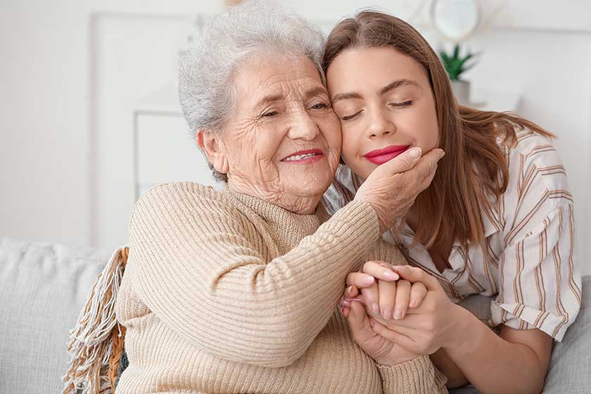 Young woman with her grandmother holding hands at home