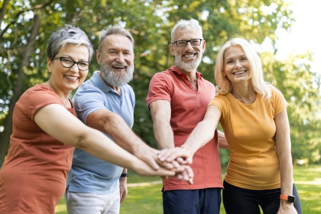 Group of cheerful senior people stacking hands after sport workout outdoors Group of cheerful senior people stacking hands after sport workout outdoors
