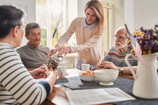 Woman holding teapot and pouring tea for the three pensioners Woman holding teapot and pouring tea for the three pensioners