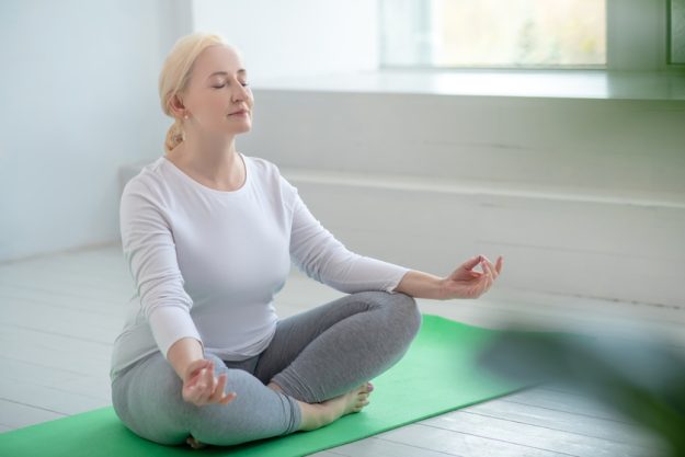 Mature blonde female sitting in lotus pose, meditating Mature blonde female sitting in lotus pose, meditating