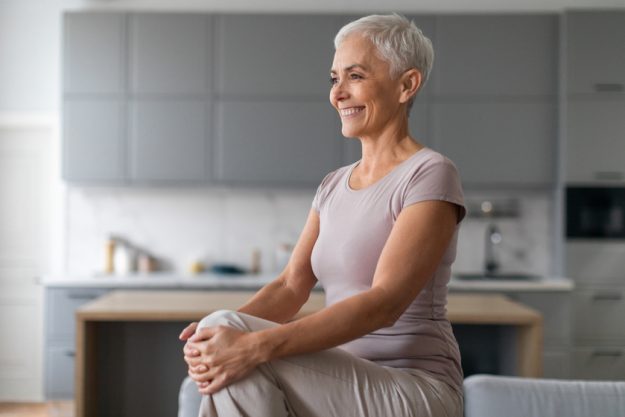 Cheerful Mature Woman Doing High Knees Exercise In Living Room Cheerful Mature Woman Doing High Knees Exercise In Living Room