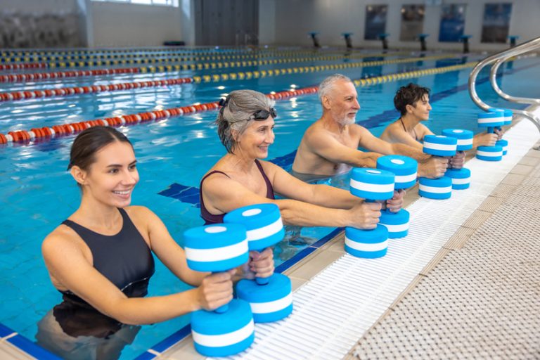 Group of seniors having an exercise with dumbbels during water aerobics class