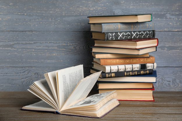 Hardcover book on wooden table against grey background Hardcover book on wooden table against grey background