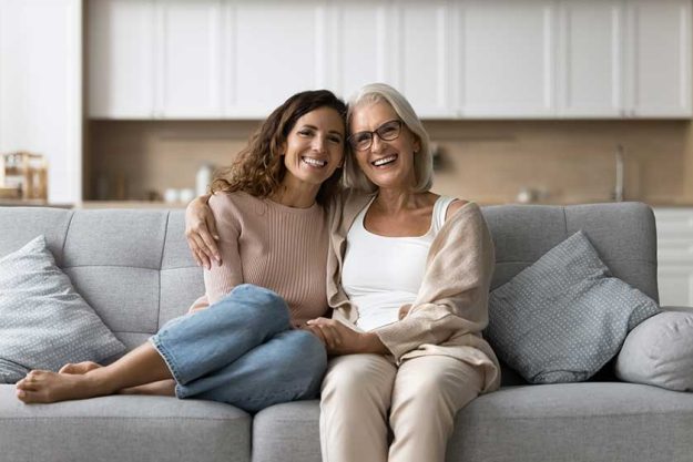 Cheerful-senior-mother-daughter-woman-sitting-home-couch-close-together Cheerful-senior-mother-daughter-woman-sitting-home-couch-close-together