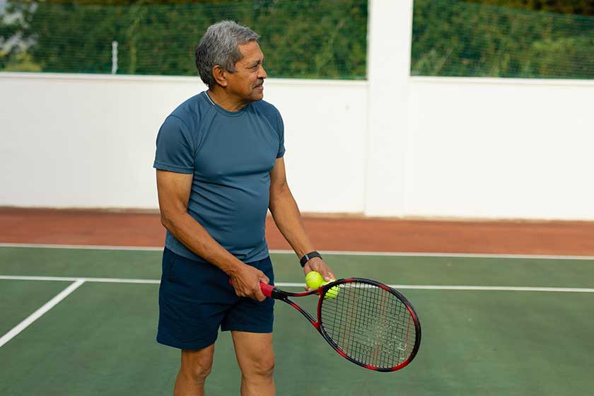 Confident-biracial-senior-man-holding-racket-ball-looking-away-while Confident-biracial-senior-man-holding-racket-ball-looking-away-while
