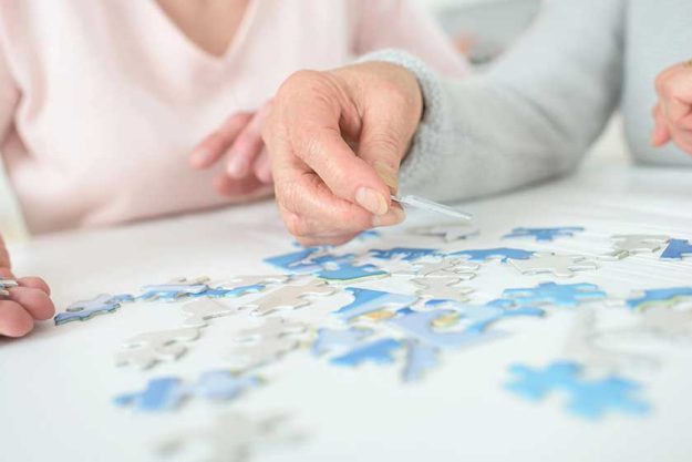 Women-playing-with-jigsaw-puzzle-on-wooden-table