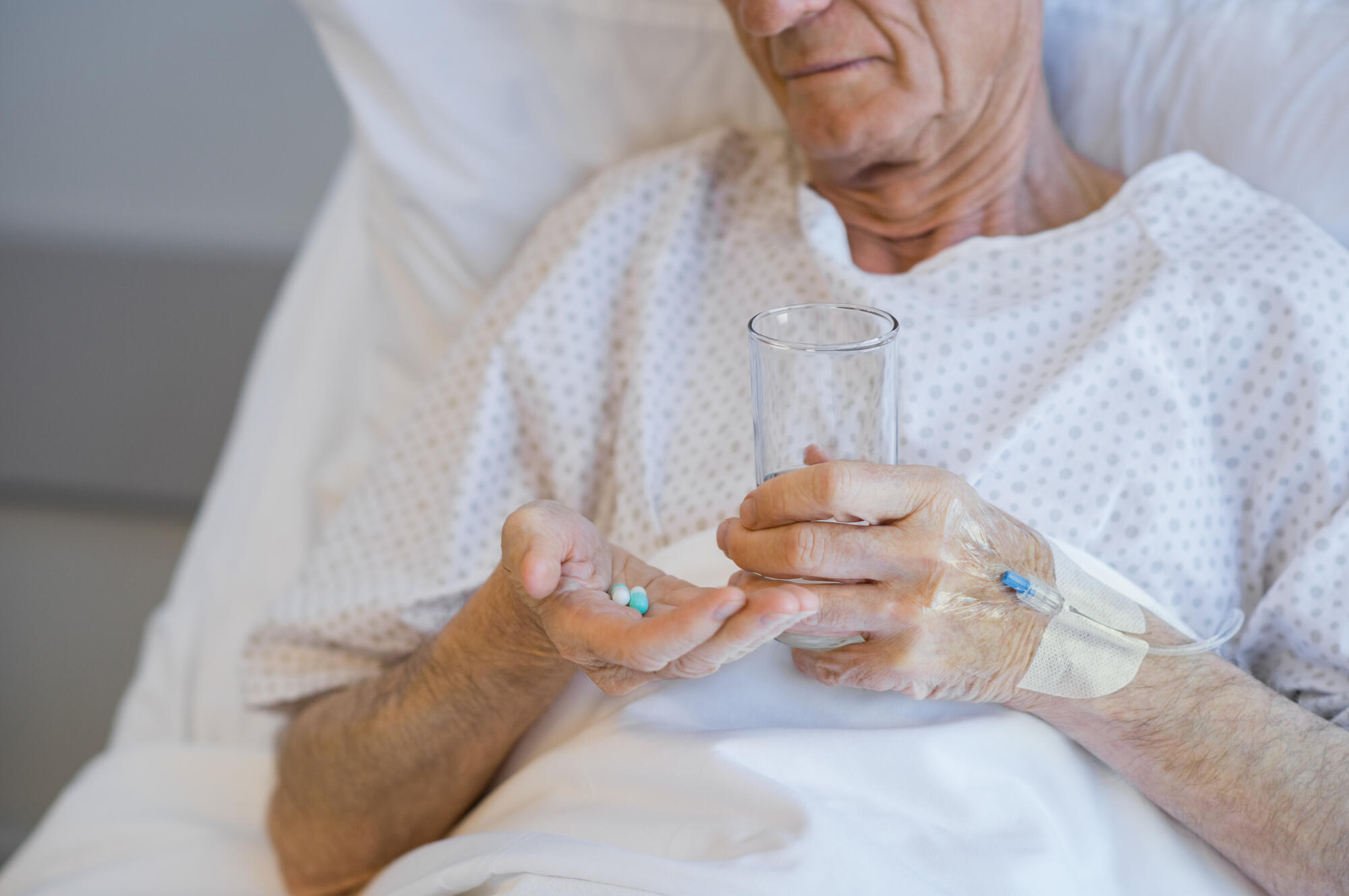 Senior,Man,Lying,On,Hospital,Bed,Taking,Medicine,With,Glass