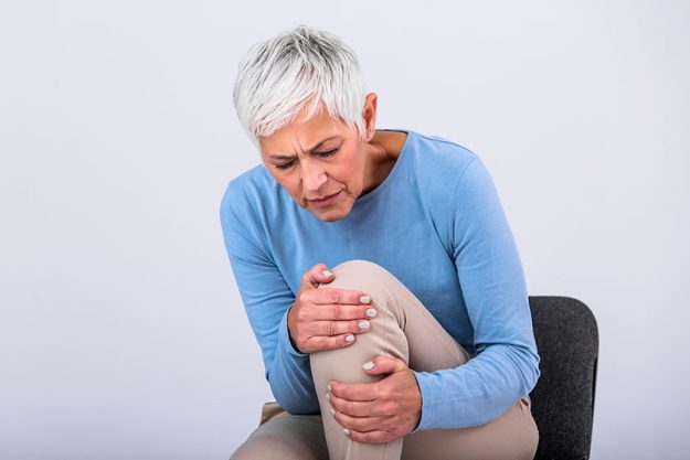 Senior woman holding the knee with pain