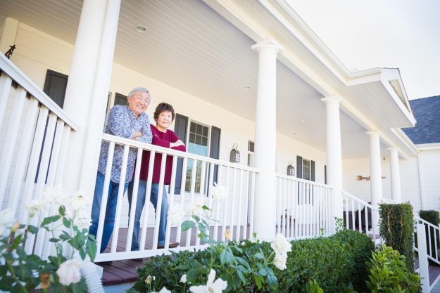 Attractive Happy Chinese Couple Enjoying Their House Outside.