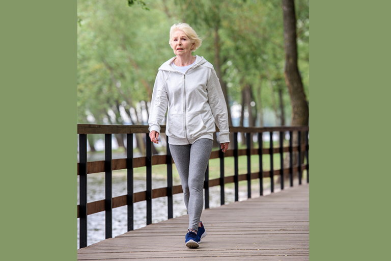 senior-woman-sportswear-walking-wooden-path