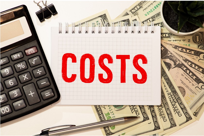 The word COSTS is written on notepad on desktop with laptop The word COSTS is written on notepad on desktop