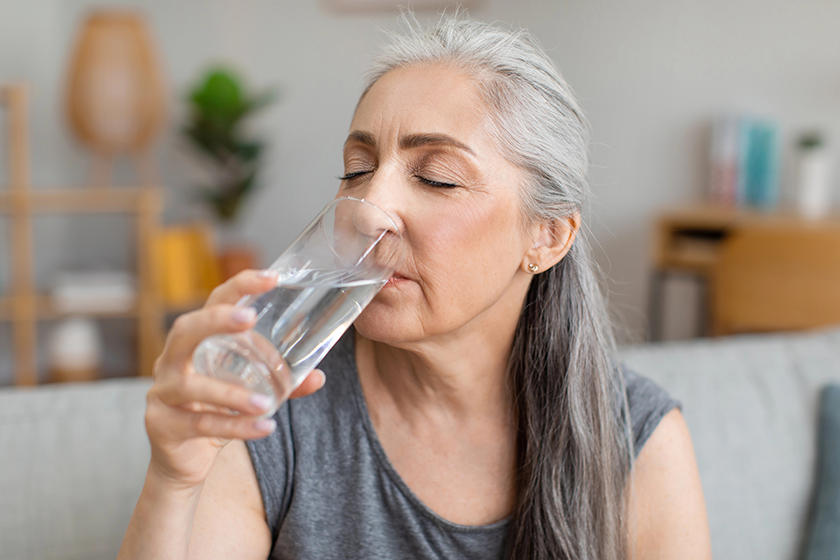 Caucasian elderly gray-haired woman drink water