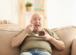 Fat senior man eating cake while sitting