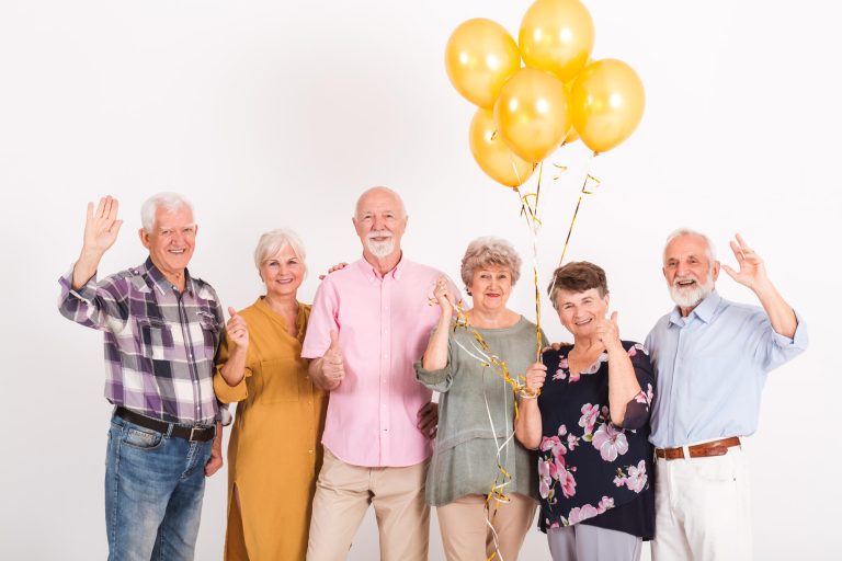 White,Interior,With,Group,Of,Senior,Happy,Friends,Holding,Bunch
