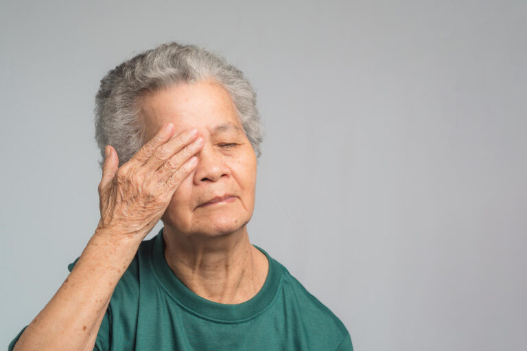 Portrait of a senior woman with eye pain while standing on a gra