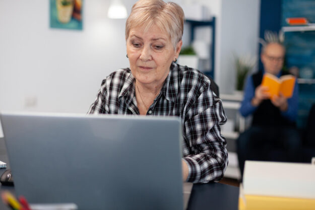 Senior lady working and pointing at computer screen