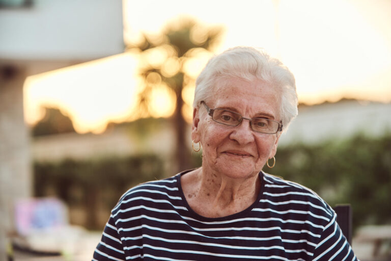 Unfiltered portrait, a real elderly woman sits gracefully in a chair, showcasing the authenticity of aging with wrinkles and a natural face