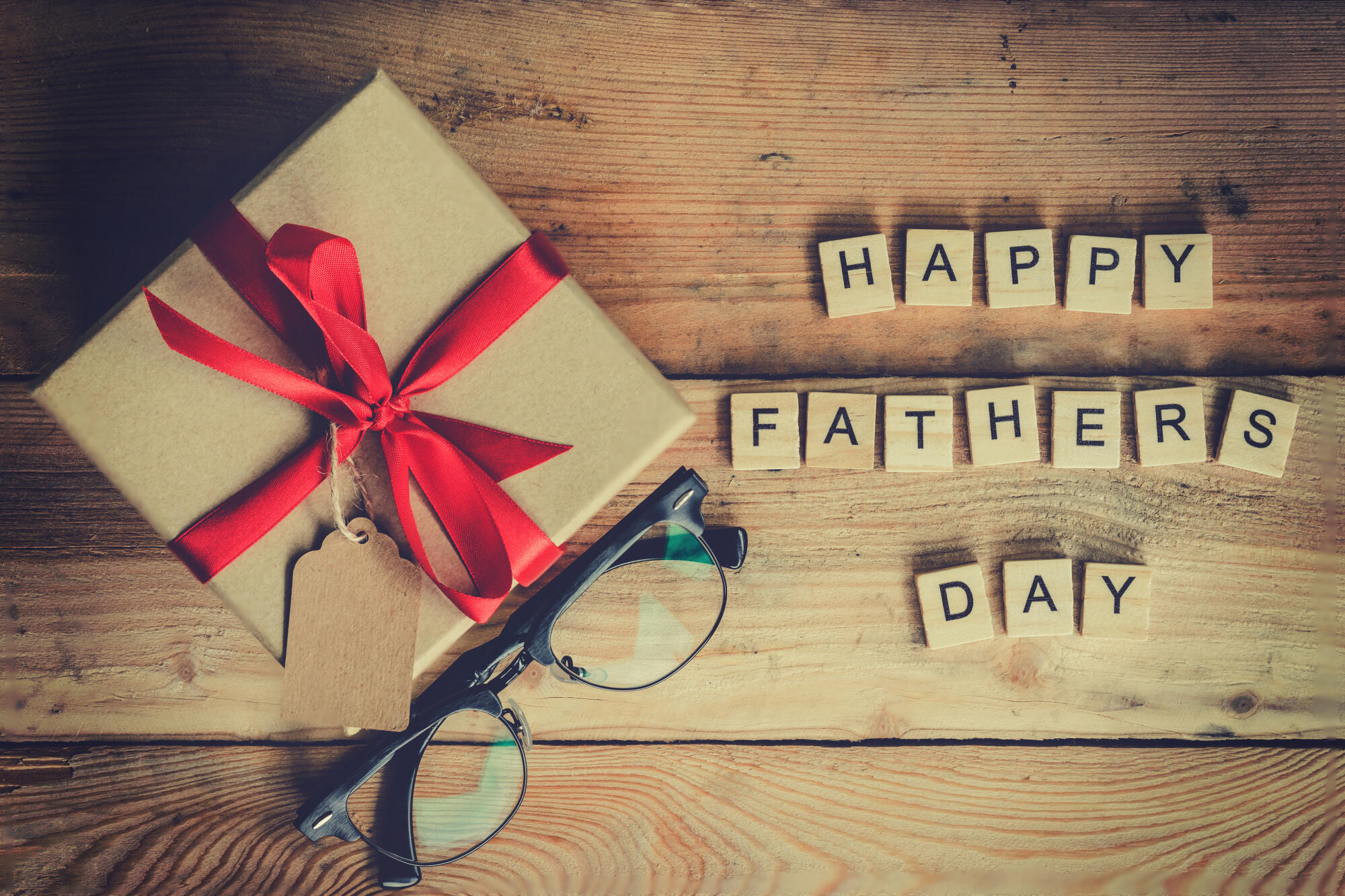 Happy father’s day block and gift box with glasses on wood backg