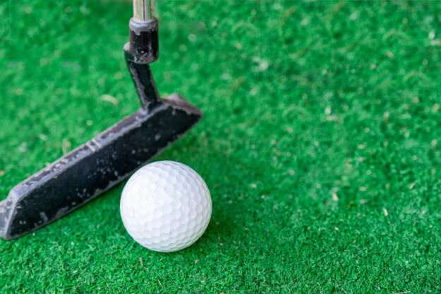 Golfer preparing on training putt with golf ball