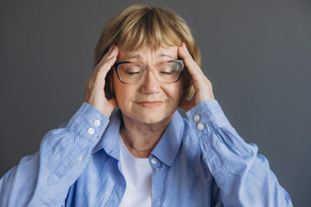 Portrait of senior woman at home with a headache, feeling pain a