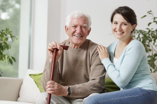 Smiling,Old,Man,Holding,A,Cane,And,Smiling,Young,Woman